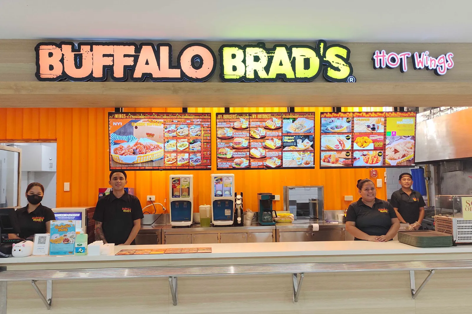 Buffalo Brad's staff behind the counter at a Cebu branch, under the lit Hot Wings sign and the menu boards.